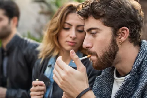Varios adultos jóvenes fuman al aire libre