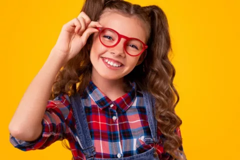 Niña sonríe sujentado sus gafas