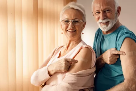 Pareja de adultos mayores sonrientes tras vacunarse contra el COVID Mujer y hombre mayores sonríen y muestran su brazo tras haberse vacunado