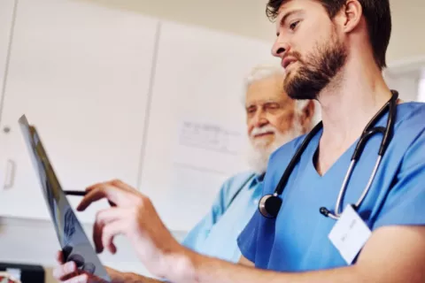 Médico muestra a su paciente con cáncer de próstata una prueba de radiología Médico muestra resultados de una prueba a un paciente mayor