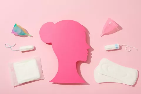 Productos menstruales como tampones, compresas o copas menstruales Silueta de mujer rosa de perfil con productos de higiene menstrual