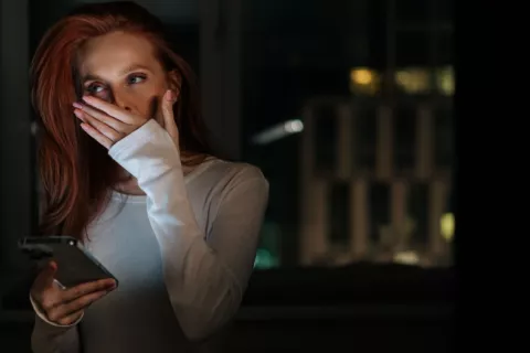 Mujer con el móvil en la mano bosteza antes de ir a dormir Mujer en una habitación a oscuras bosteza con el móvil en la mano