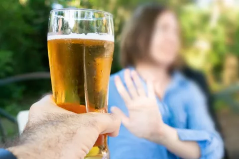 Mujer borrosa rechaza con la mano la cerveza que le ofrecen