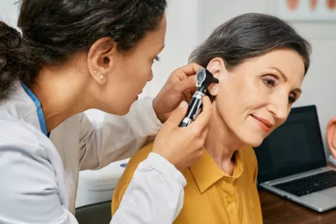 Mujer de mediana edad en el otorrino Otorrina revisa el oído a una mujer de mediana edad