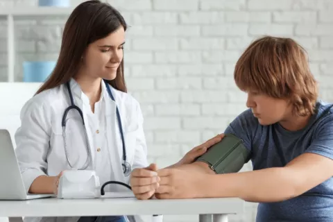 Doctora toma la tensión arterial a un adolescente