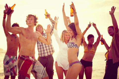 Grupo de personas en la playa bebiendo alcohol