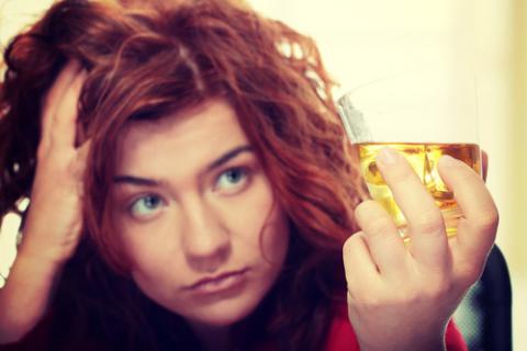 Mujer con un vaso de alcohol en la mano