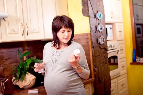 Embarazada con un envase de antibióticos en la mano