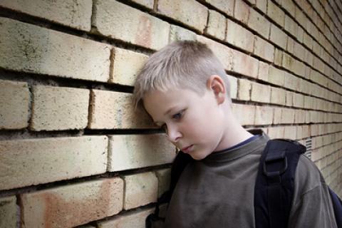 Niño triste con la cabeza apoyada en una pared