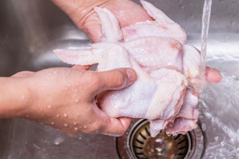 Persona lavando alitas de pollo en el grifo