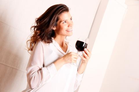 Una joven sostiene una copa de vino tinto