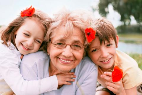 Una abuela posa sonriente con sus dos nietos