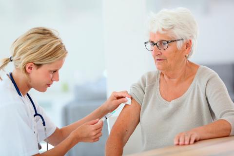 Una profesional sanitaria vacuna a una anciana
