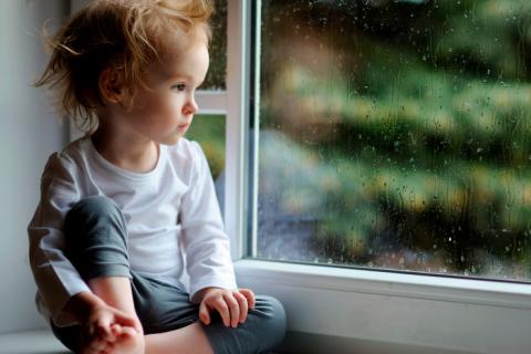 Niño triste mirando la ventana