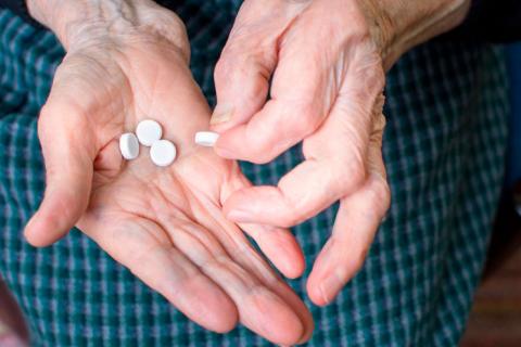 Persona con alzhéimer tomando una pastilla de aspirina