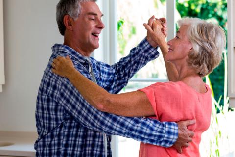 Una pareja de adultos mayores baila en la cocina de su casa