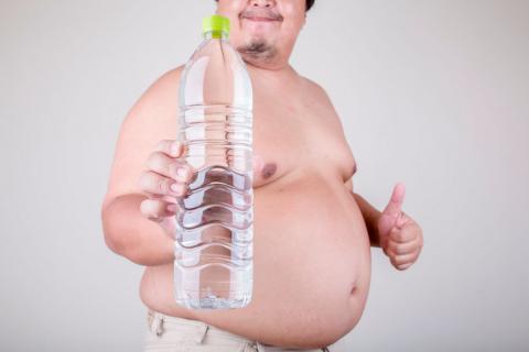 Hombre obeso con una botella grande de agua en la mano