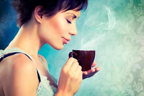 Una mujer a punto de tomar una taza de café muy caliente