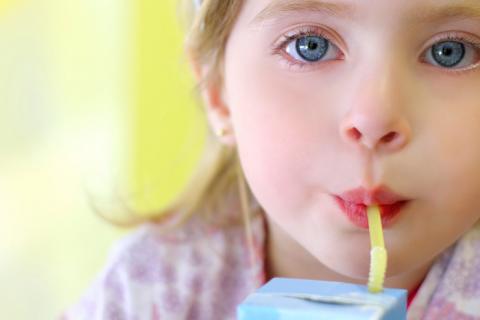 Una niña tomándose un zumo envasado en un tetrabrik