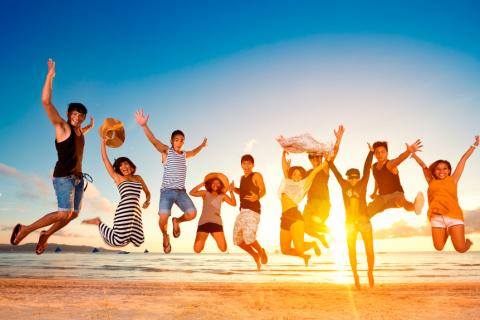 Jóvenes felices saltando en la playa