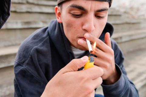 Adolescente encendiéndose un cigarro