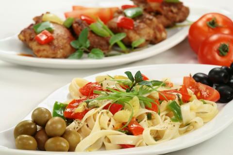 Platos con espagueti con verduras y aceitunas y pollo