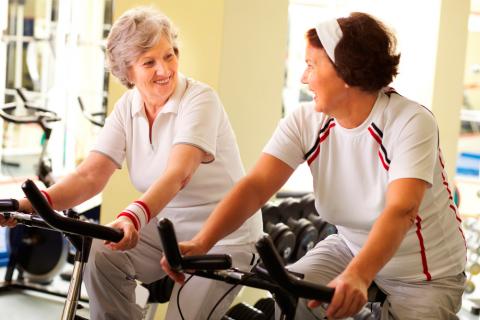 Dos mujeres mayores realizan ejercicio en bicicleta estática