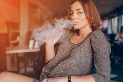 Mujer embarazada fumando con un cigarrillo electrónico