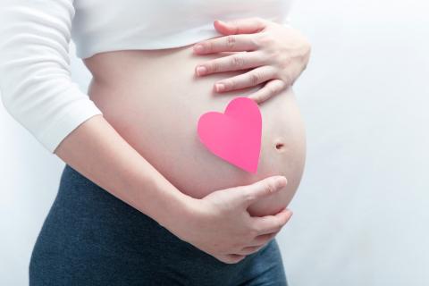 Mujer embarazada con un corazón rosa