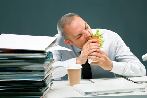 Trabajador estresado comiendo comida rápida