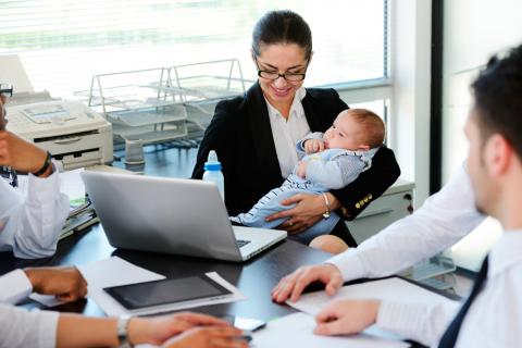 Una mujer sostiene a su bebé durante una reunión de trabajo