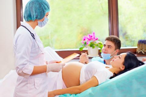 Mujer embarazada y su pareja en el hospital escuchan las indicaciones de una doctora