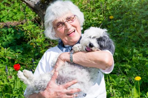 Una mujer mayor sonríe mientras sostiene a un perro en brazos