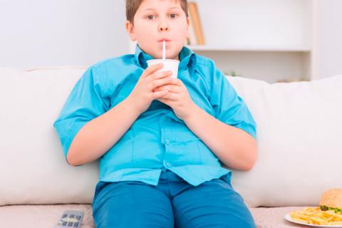 Adolescente sedentario bebe y come mientras ve la tele