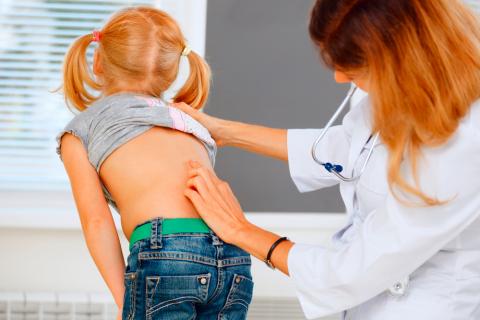 Una doctora examina la espalda de una niña
