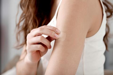 Una mujer se coloca un parche anticonceptivo en el brazo