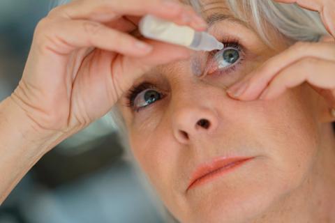 Mujer mayor echándose lágrimas artificiales para el ojo seco