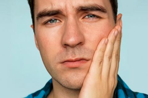 Persona con dolor derivados de bacterias que causan periodontitis