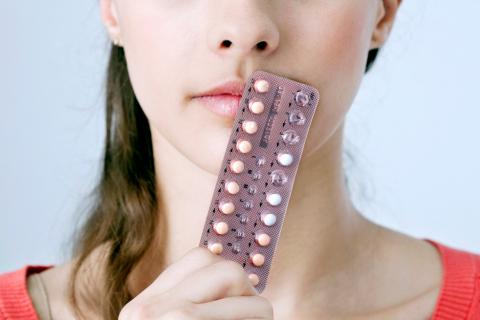 Una joven sostiene un blíster con píldoras anticonceptivas