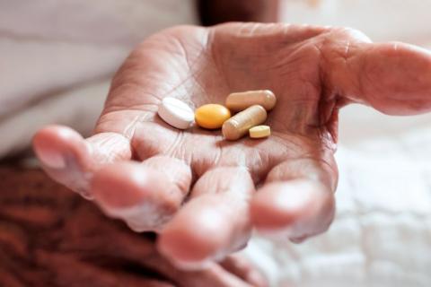 Persona mayor con algunas píldoras en la mano para paliar los síntomas de alzhéimer