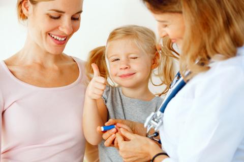 Una doctora con una muestra de sangre de una niña pequeña que se muestra feliz