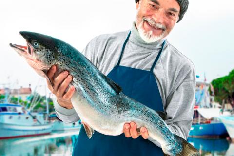 Un pescador sujeta un salmón en sus manos