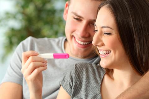 Una pareja mira sonriente un test de embarazo