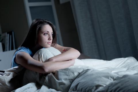 Una joven sentada en la cama tras despertarse durante la noche
