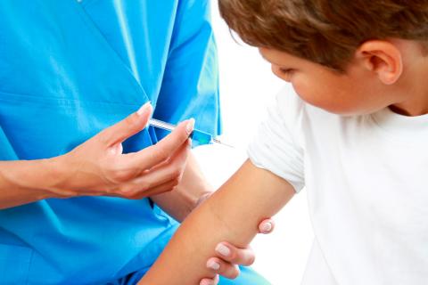 Un profesional sanitario vacuna a un niño