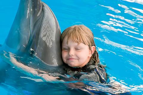 Una niña abraza a un delfín en el agua