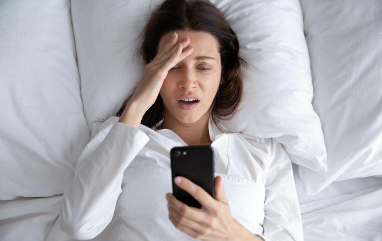Mujer mirando con angustia el dispositivo móvil creyendo que no ha dormido suficiente