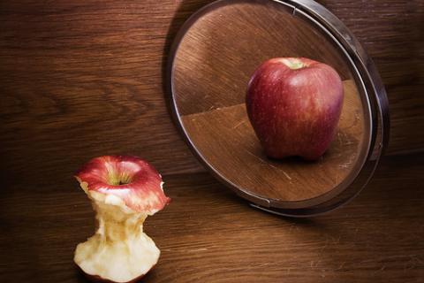 Manzana comida y manzana entera al espejo, concepto de anorexia