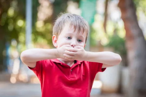Concepto de mutismo selectivo, niño tapándose la boca
