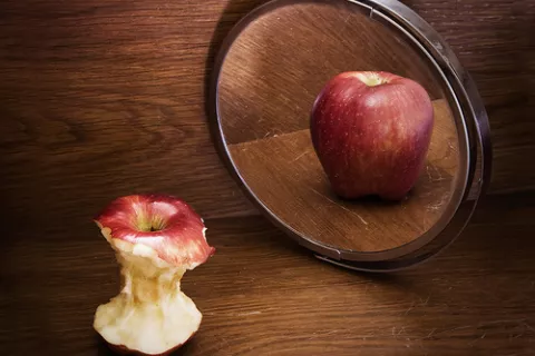 Manzana comida y manzana entera al espejo, concepto de anorexia